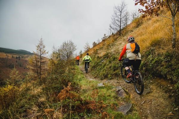 three MTBers riding e-bikes up a steep incline in the Welsh mountains
